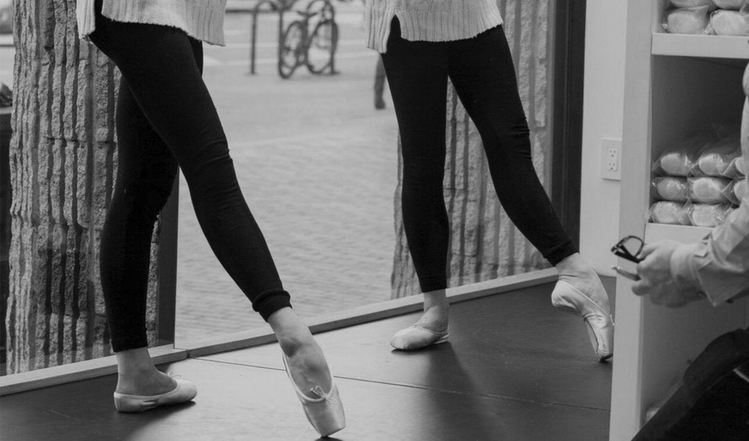 Two young dancers dancing en pointe at the barre being fitted for pointe shoes by a professional BLOCH pointe shoe fitting