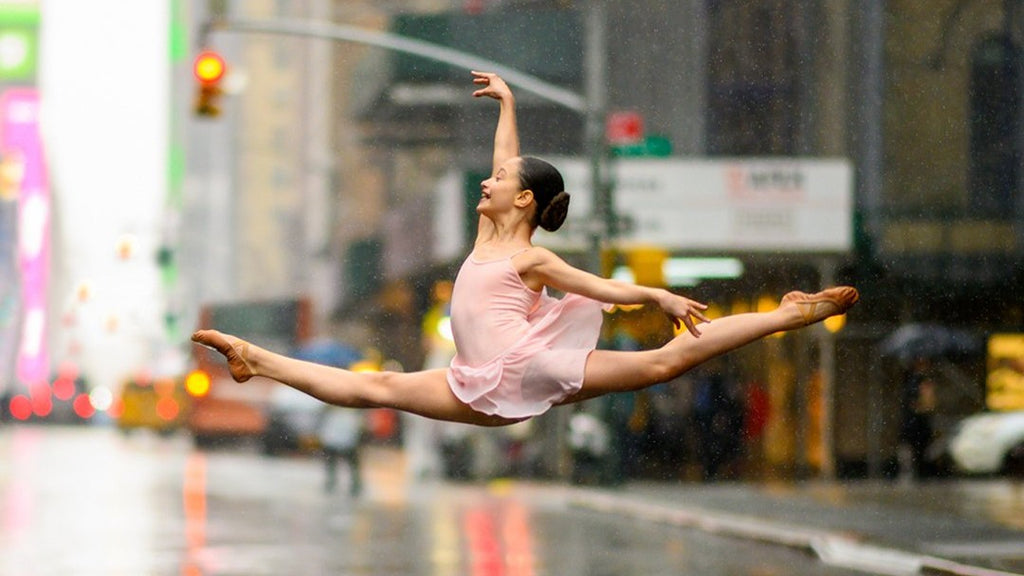 Young dancer leaping through New York City wearing a pink BLOCH skirted leotard