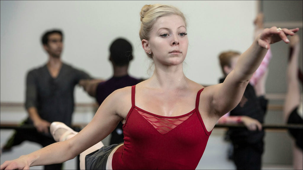 A female dancer practising pointe work at the barre during a ballet class 